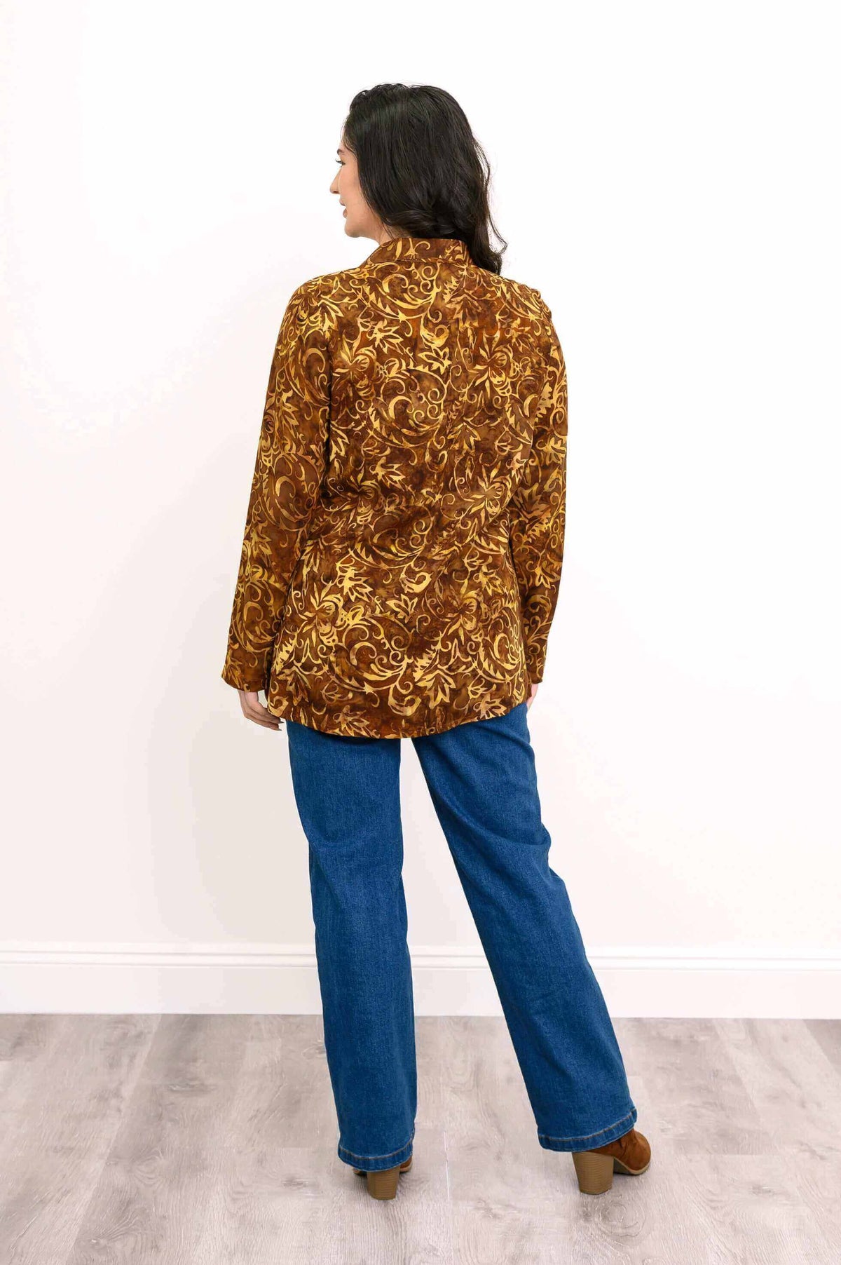 Back view of woman wearing an autumn gold smocked long sleeve shirt with floral pattern