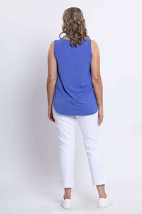 Rear view of a woman showing the back of an azure blue sleeveless tank top and white pants