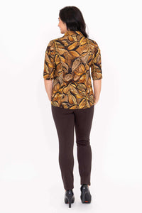 Back view of woman wearing bamboo-linen leaf print blouse and brown pants