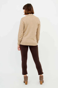 Back view of a woman wearing a beige cardigan and brown pants with heeled boots