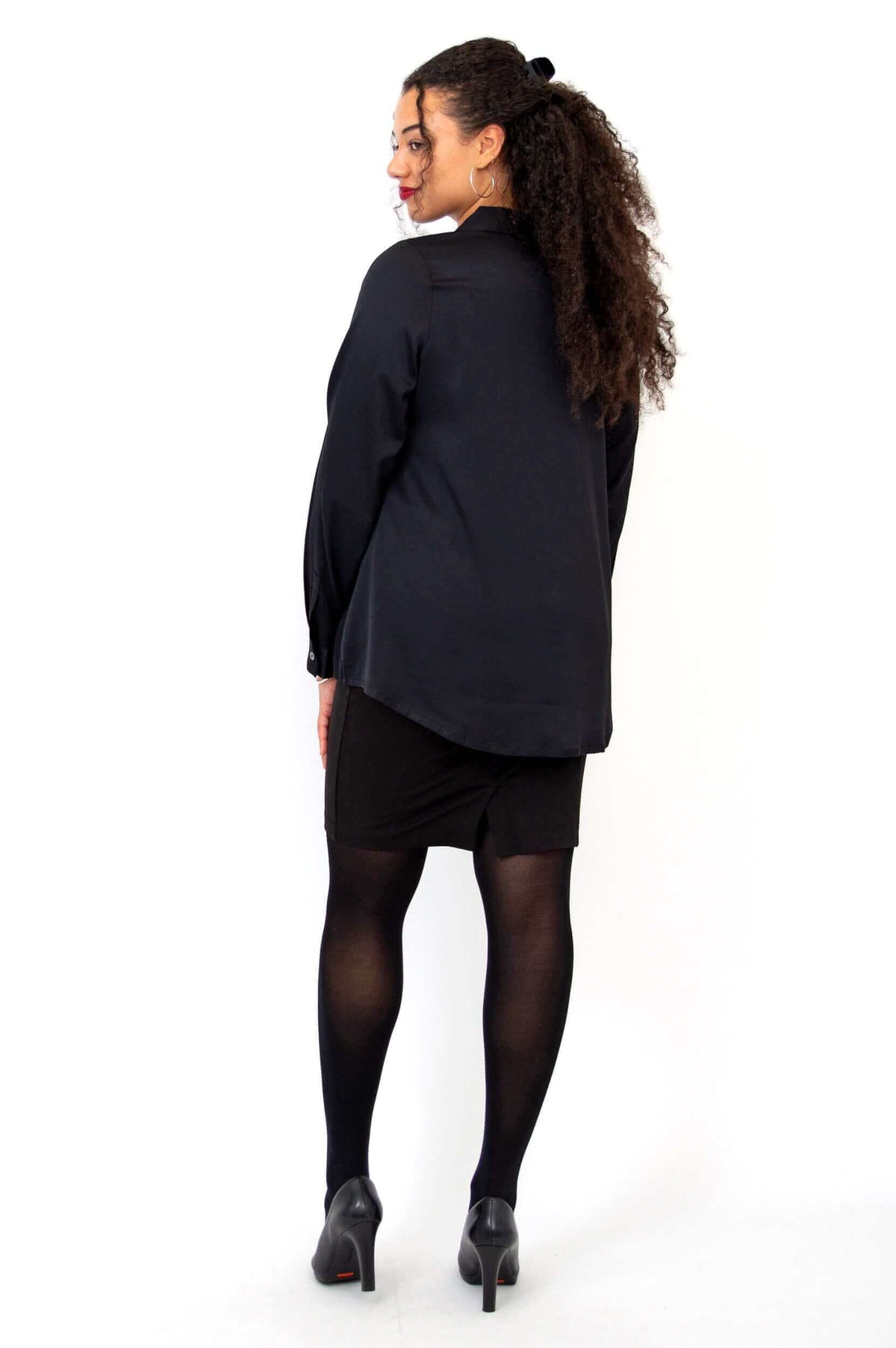 Back view of model wearing black Sylvie Blouse showing loose fit and curved hem