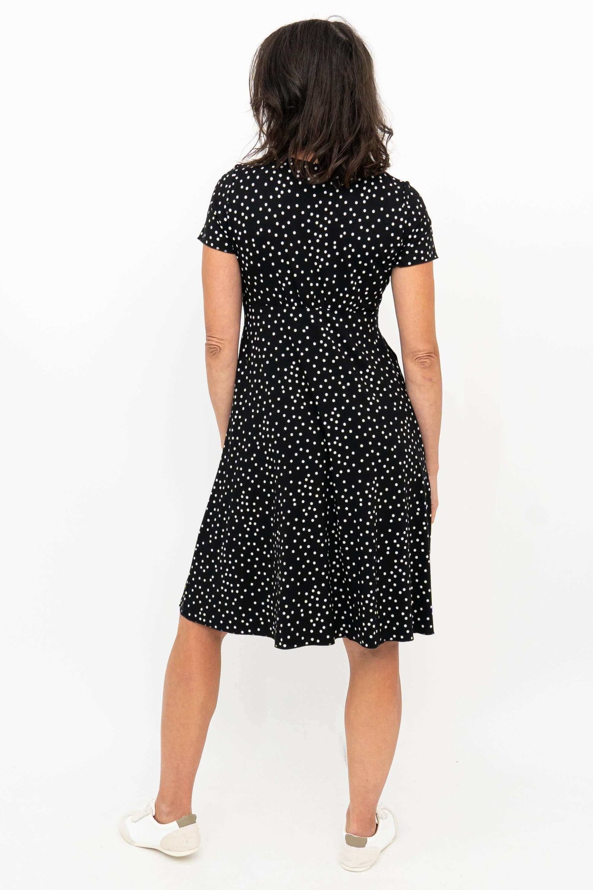 Back view of woman wearing black and white polka dot crossover dress with short sleeves