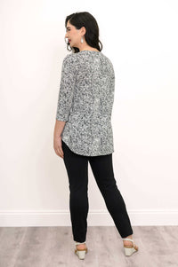 Back view of woman wearing black and white rose print top with curved hem