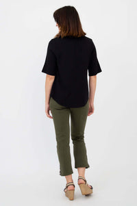 Back view of woman wearing black blouse and olive pants