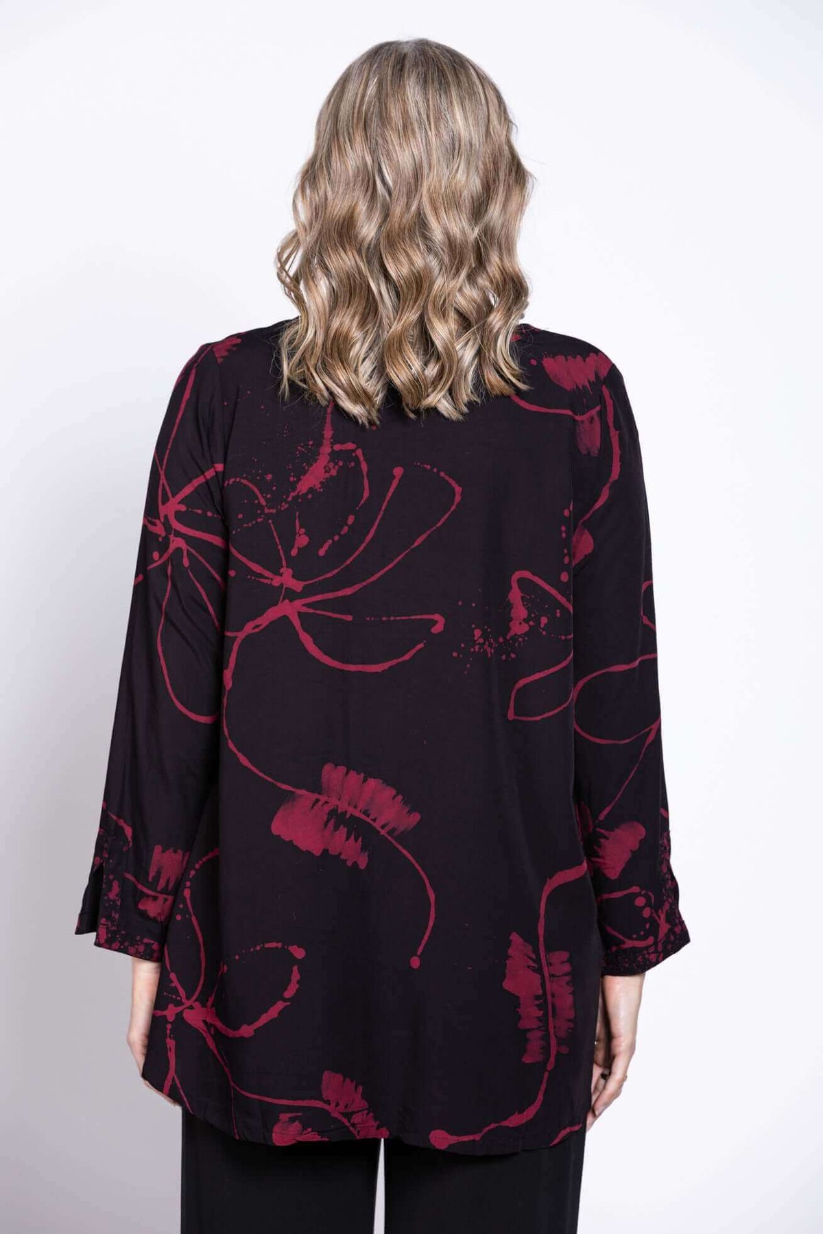 Back view of black blouse with berry floral design, model’s hair down