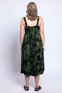 Back view of woman in black dress with green leaf print and shirred bodice