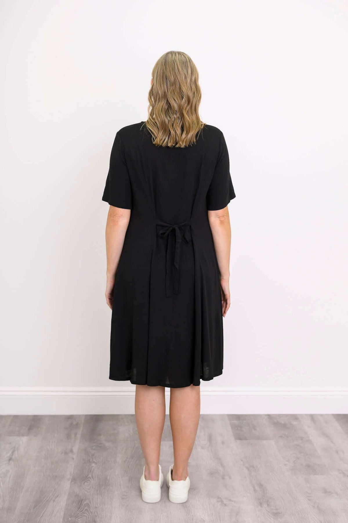 Back view of a woman in a black dress showing tie belt detail