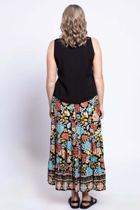 Back view of a woman wearing a black top and black floral maxi skirt with colorful pattern