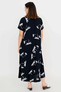 Back view of model in black short sleeve dress with white floral design and pockets