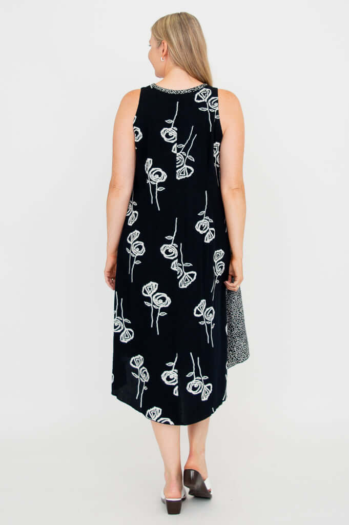 Back view of woman in black tank dress with white botanical pattern and contrast panels