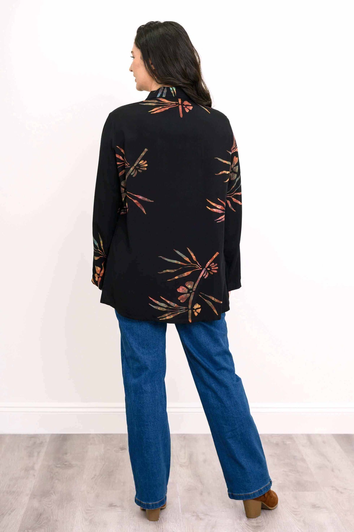 Back view of a woman wearing a black tunic with subtle floral designs