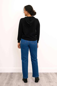 Back view of a woman wearing a black wool-cashmere hoodie and blue jeans