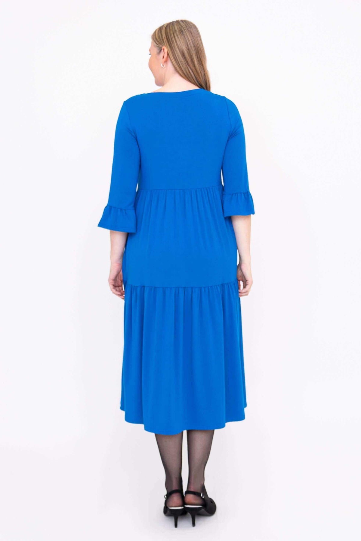 Back view of a woman wearing a blue tiered midi dress with ruffle sleeves