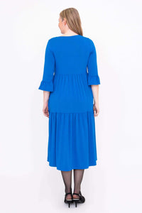 Back view of a woman wearing a blue tiered midi dress with ruffle sleeves