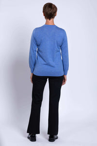 Back view of woman wearing blue Merino wool V-neck sweater