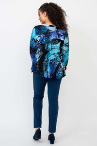 Back view of woman wearing blue abstract print cropped hi-lo blouse and navy pants
