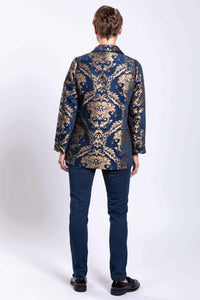 Back view of ornate blue and gold jacquard coat worn by woman, showing full rear detail