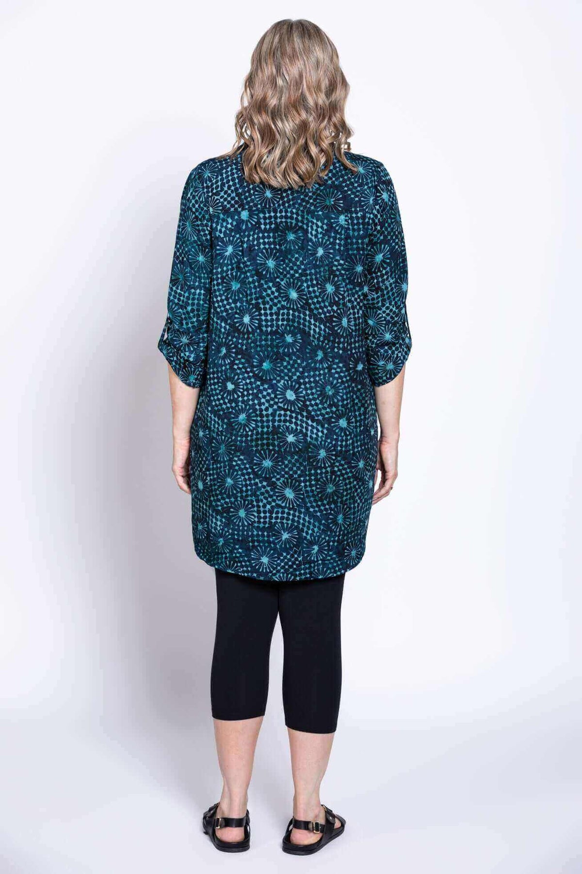Back view of woman in blue and teal batik blouse with 3/4 length sleeves