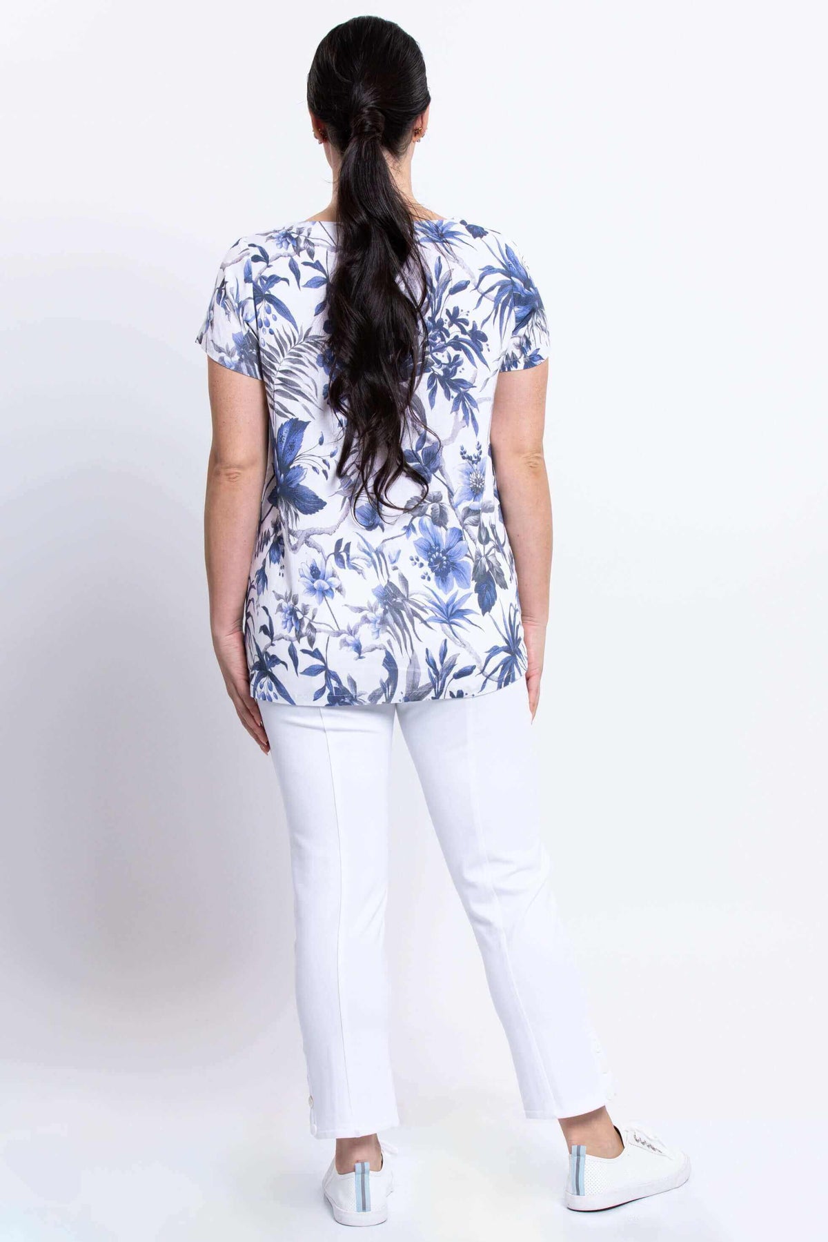 Back view of woman in blue and white floral top with white pants