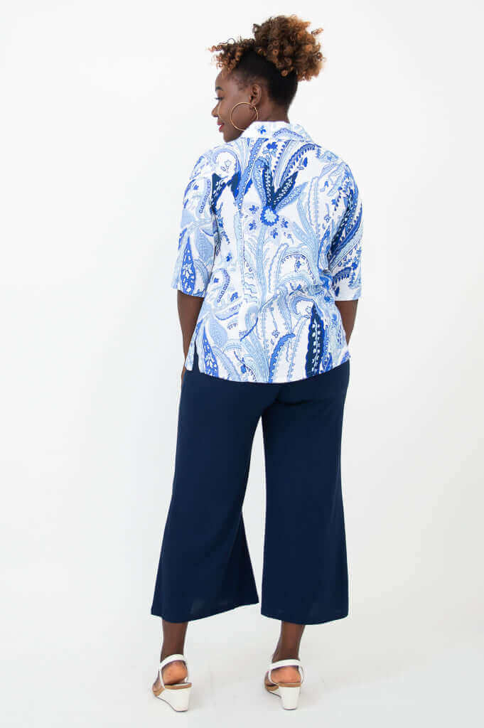 Back view of woman wearing blue and white patterned blouse and navy pants
