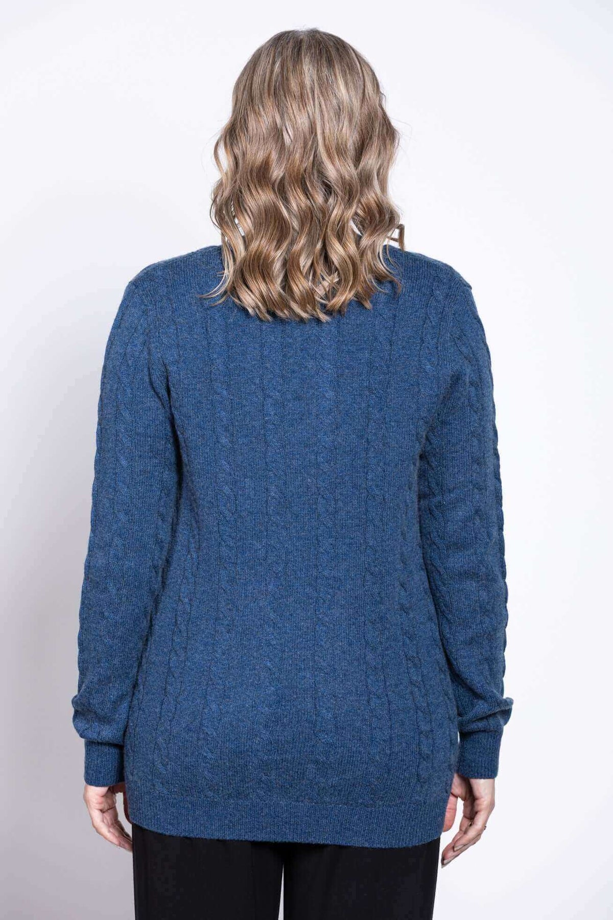 Back view of woman wearing a blue cable knit cardigan