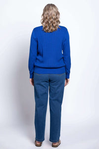 Rear profile view showing the textured cable knit design and ribbed hem on a bright blue sweater.