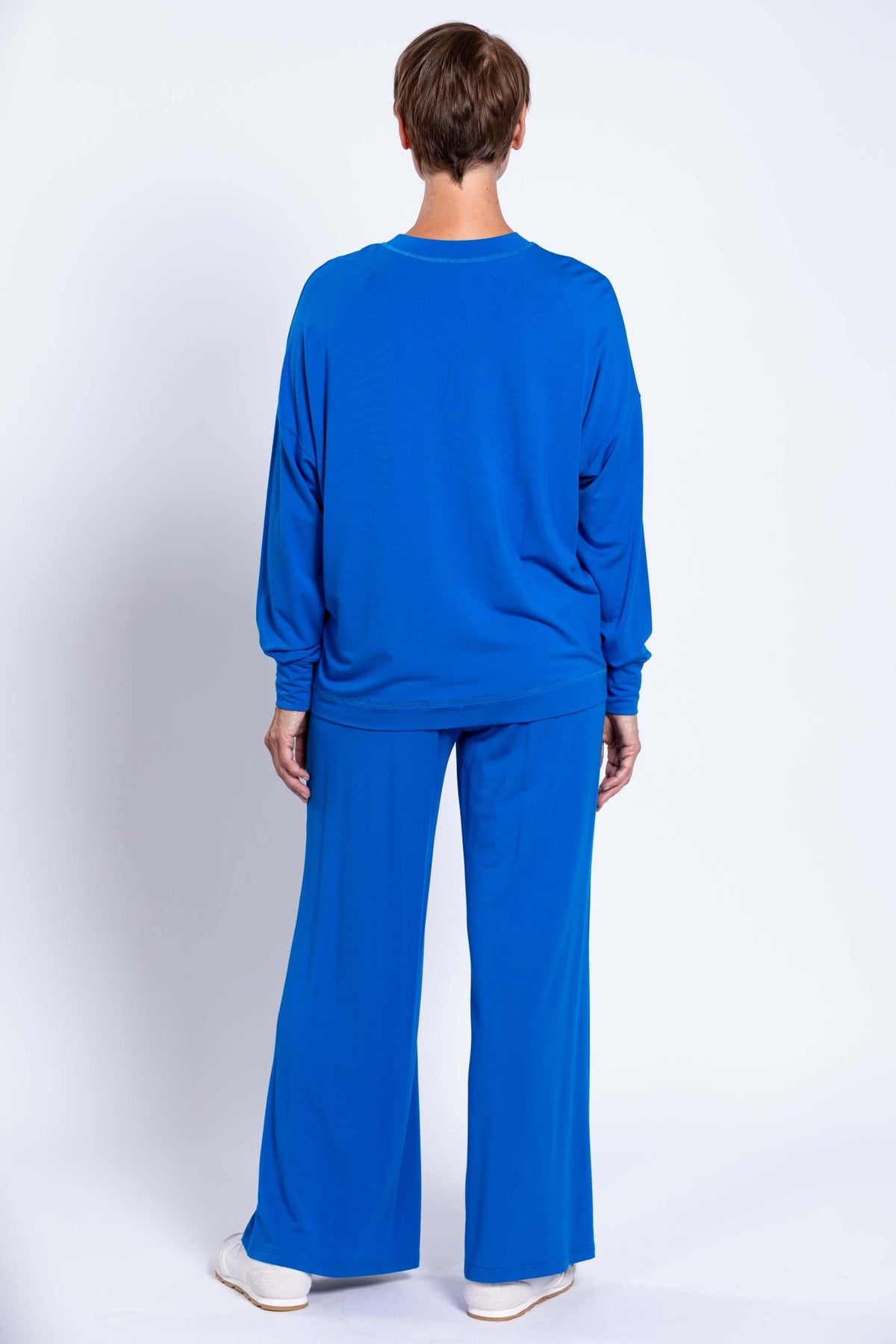 Back view of woman in blue drop shoulder crew neck top and wide-leg pants