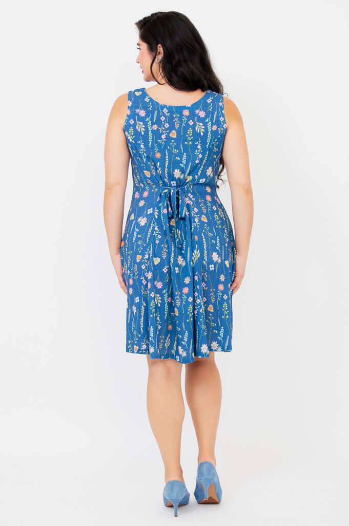 Back view of woman in blue floral A-line dress showing scoop neckline and tied waist