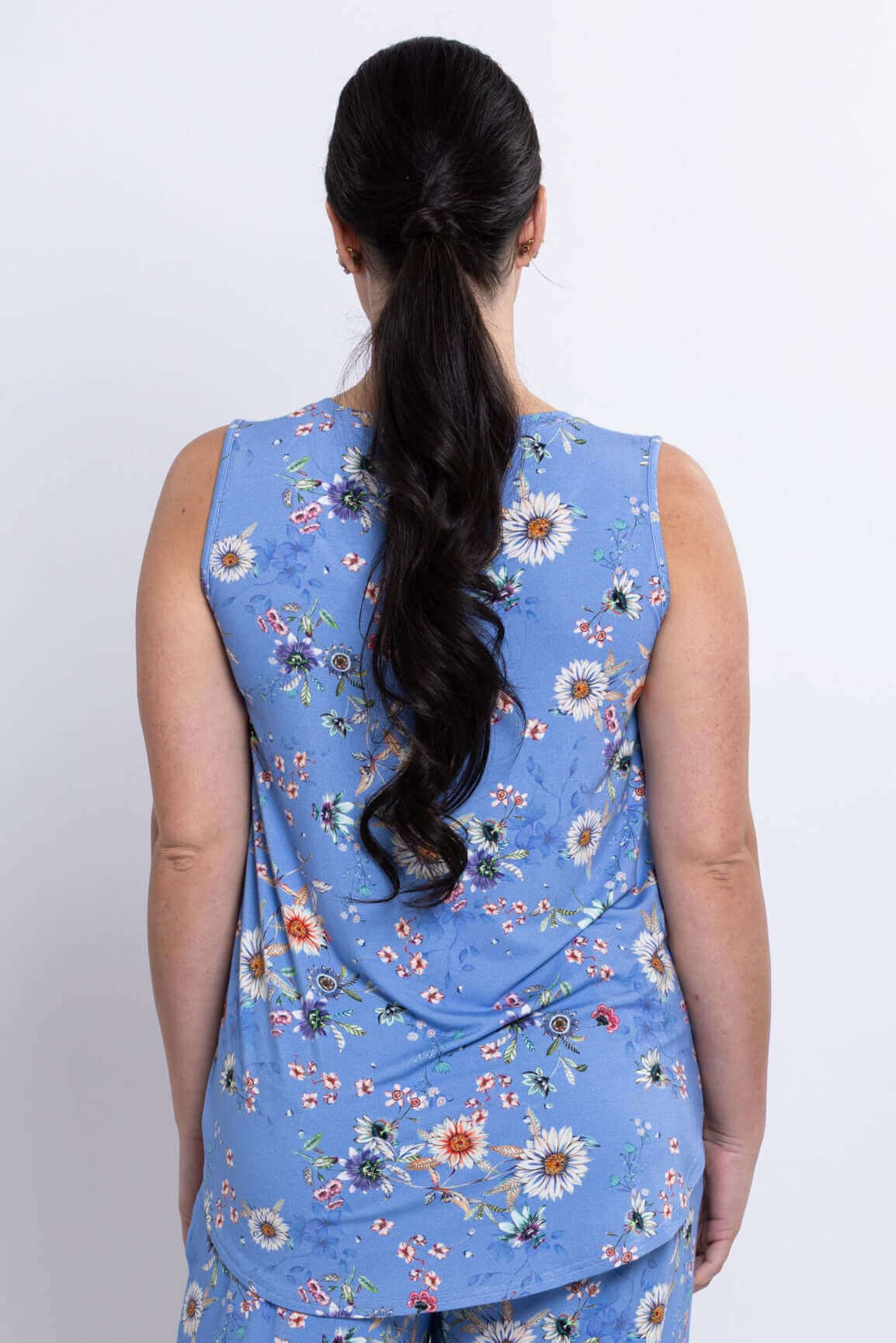 Back view of woman wearing a blue floral tank top with flowing hem