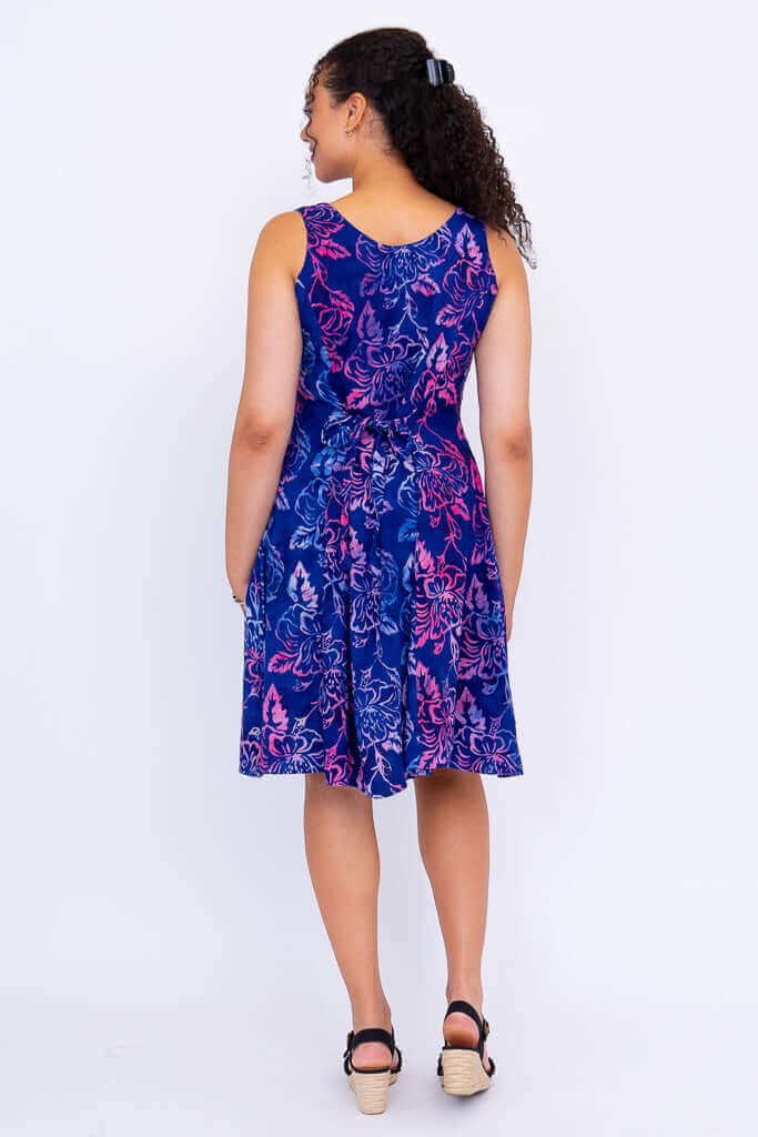 Back view of model wearing blue floral sleeveless dress with tie-belt
