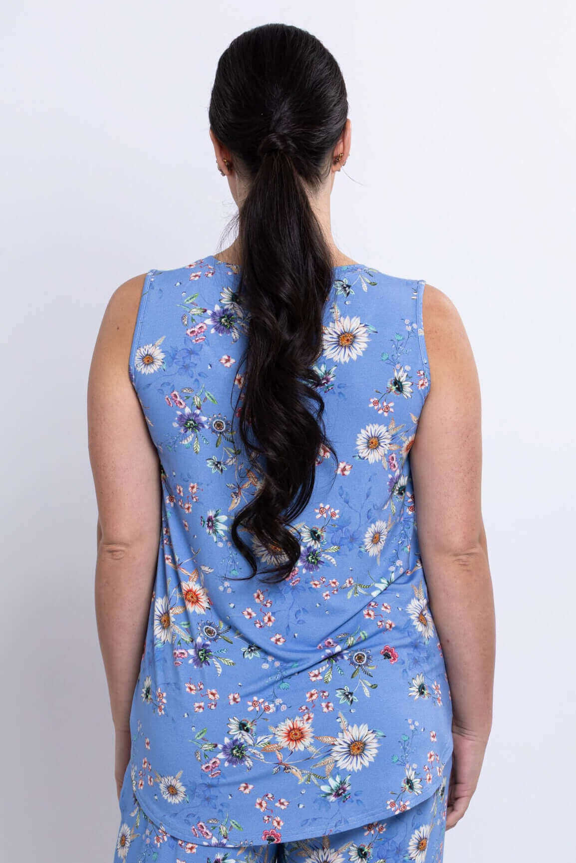 Back view of woman in blue floral sleeveless top with ponytail
