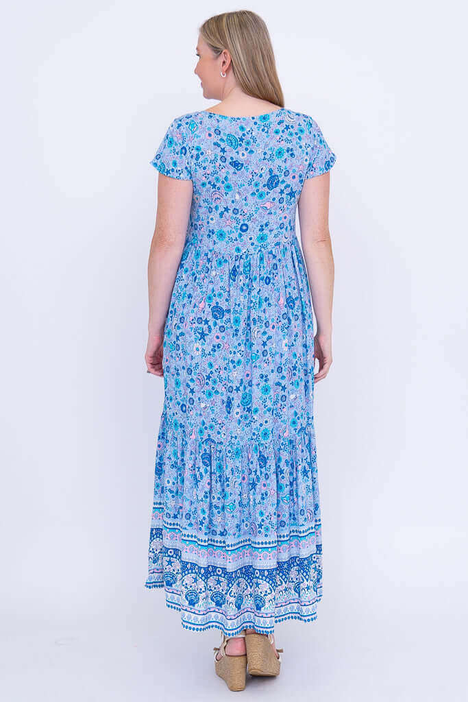 Back view of woman in blue floral tiered maxi dress