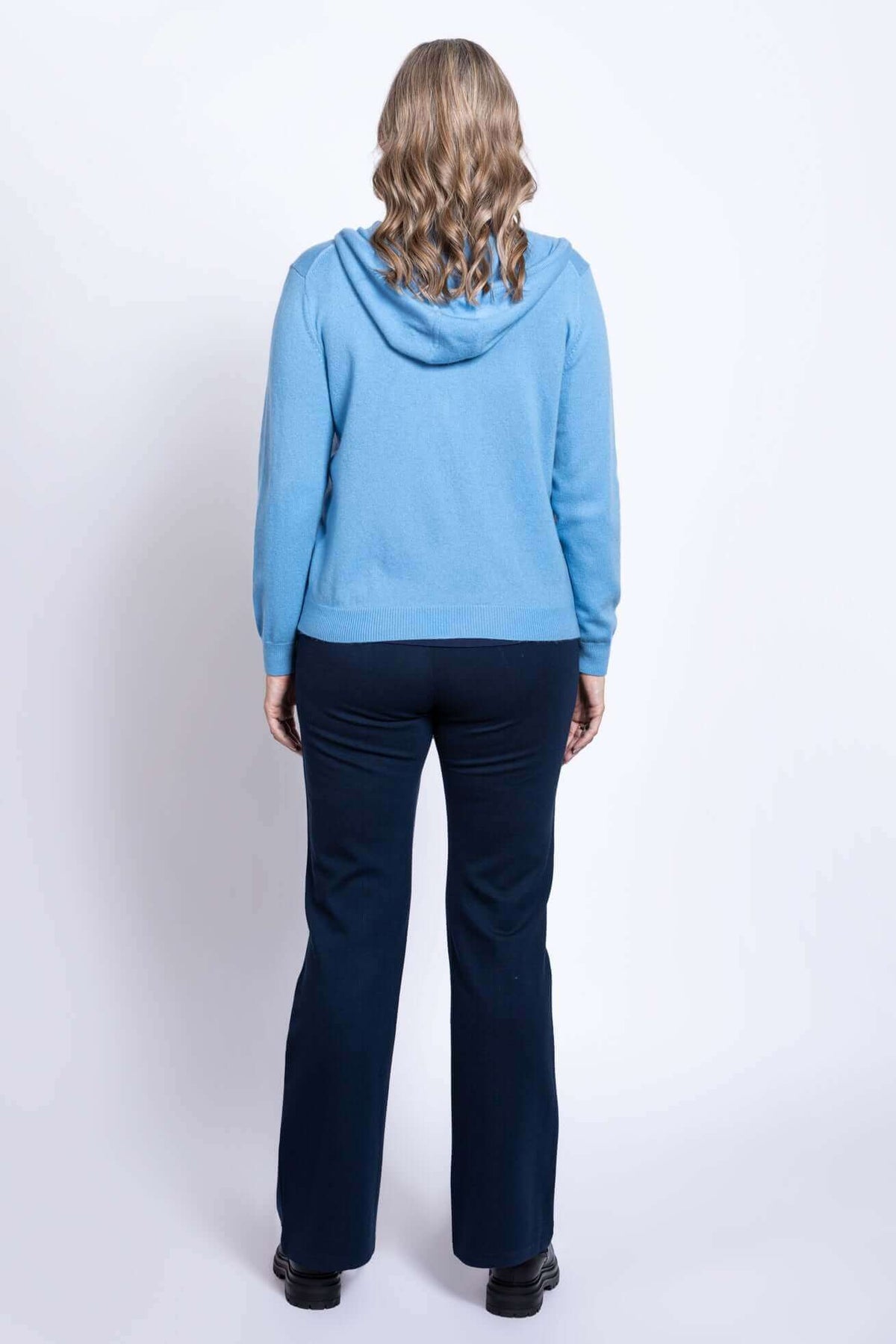Back view of woman wearing blue hoodie and navy pants