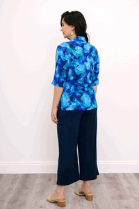 Back view of a model wearing blue patterned blouse and navy wide-leg pants
