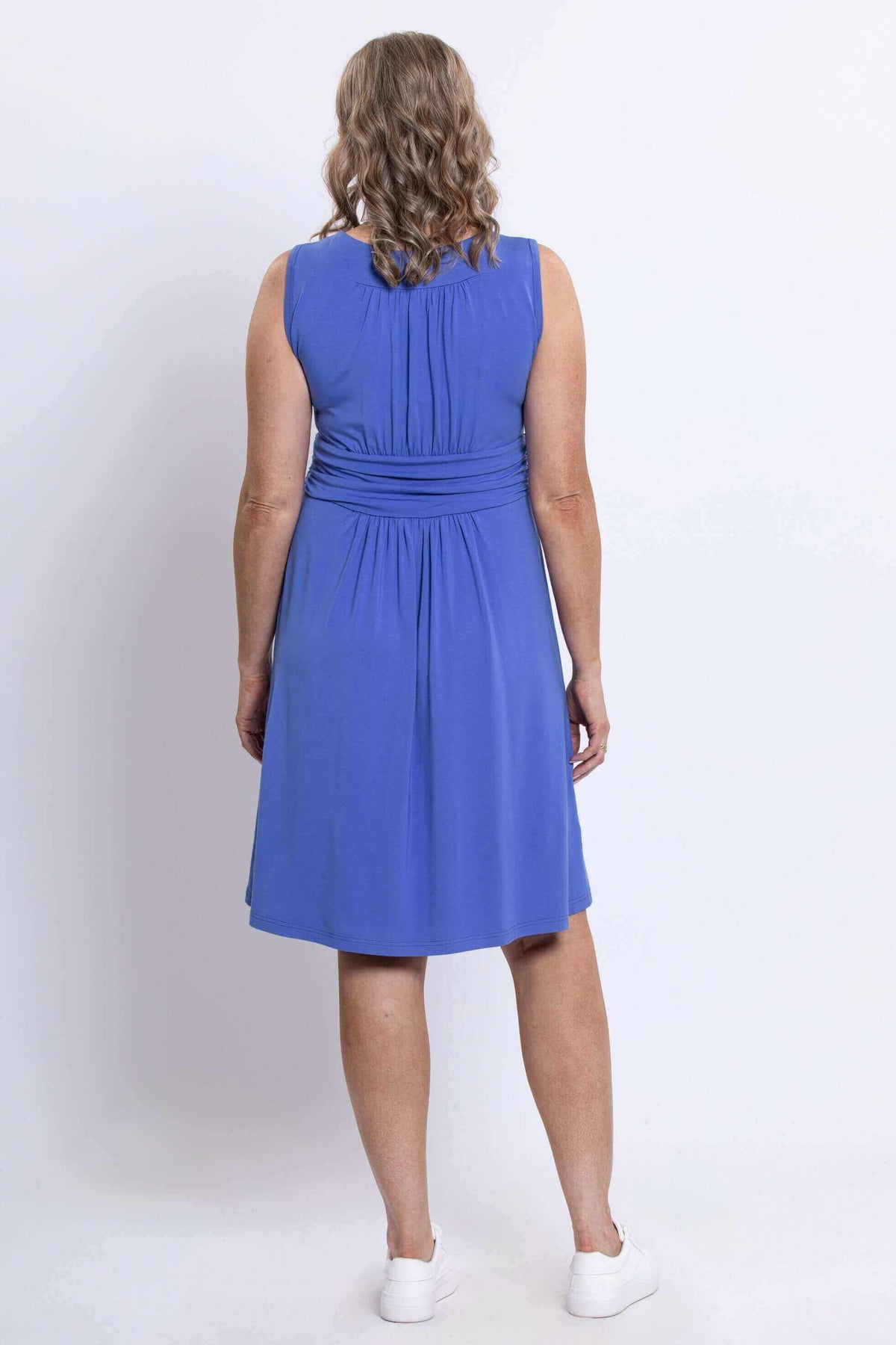 Back view of a woman wearing a blue ruched dress showing gathered fabric and fit
