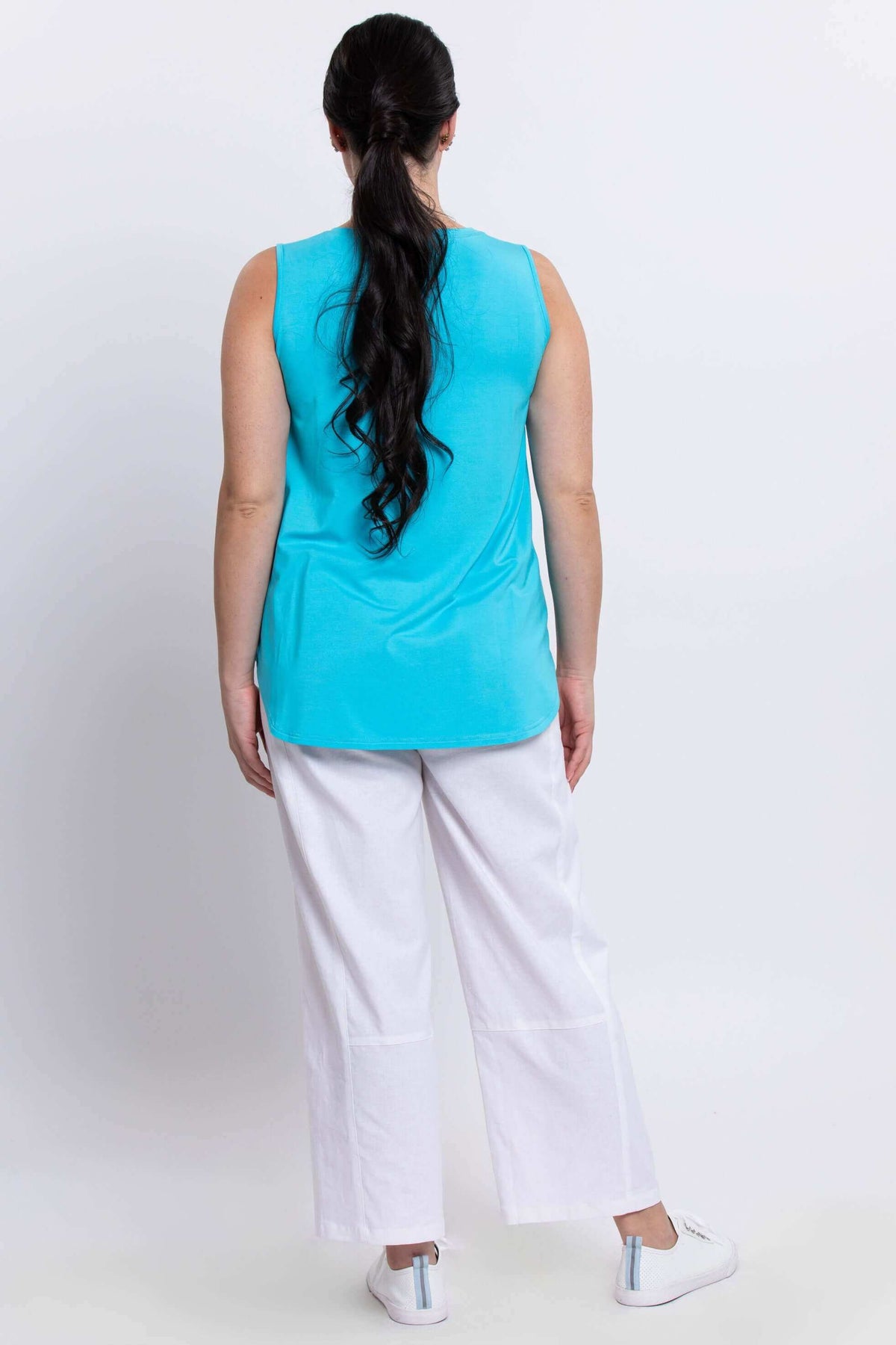 Back view of model wearing a blue tank top with white pants