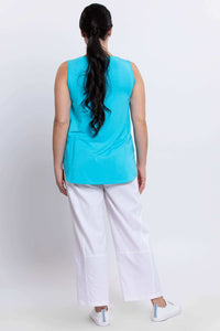 Back view of model wearing a blue tank top with white pants