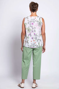 Back view of woman wearing botanical print tank top and green pants with white sandals