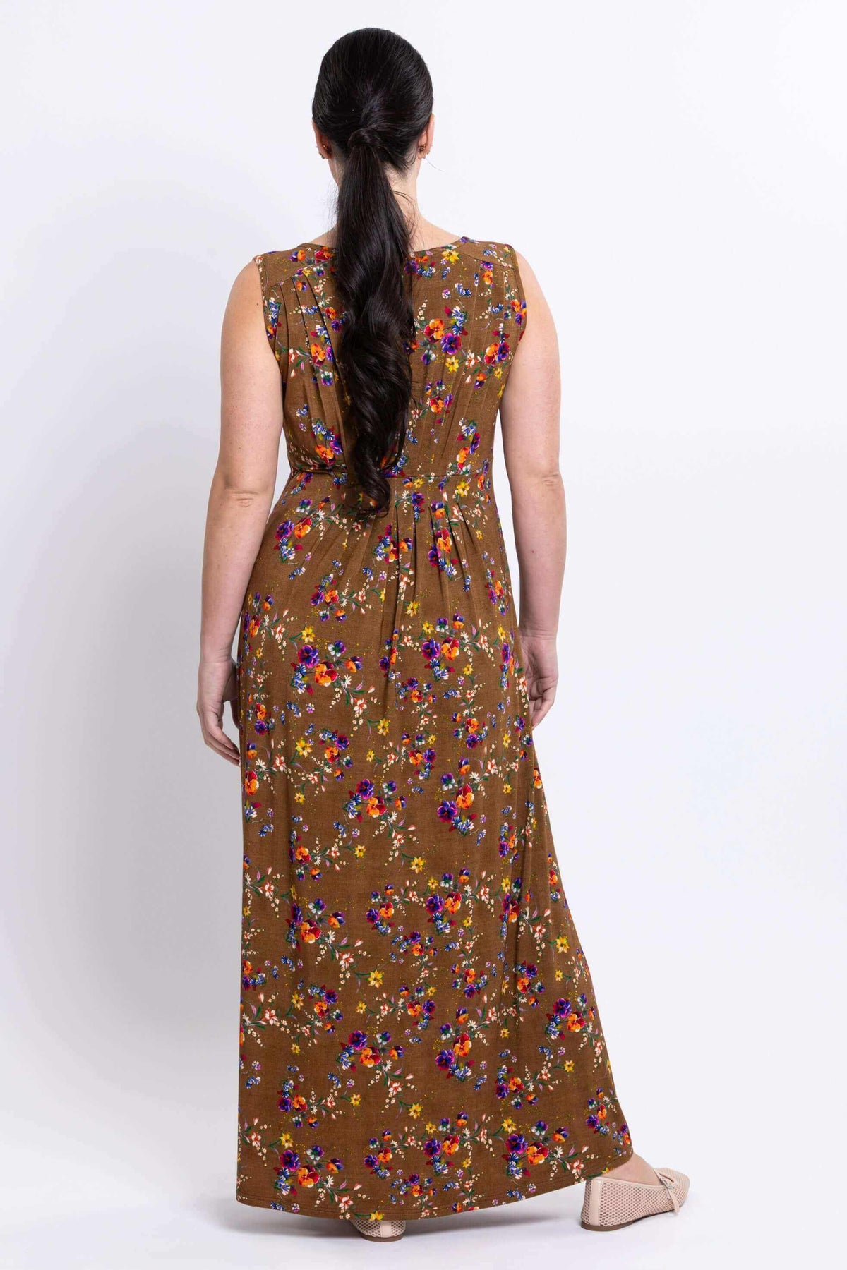 Back view of model wearing the brown floral sleeveless maxi dress with waist pleating