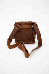 Back view of a brown leather crossbody bag highlighting the exterior pocket and strap details