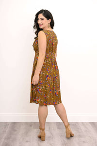 Back view of woman in brown sleeveless floral dress, showing pleat and fit details