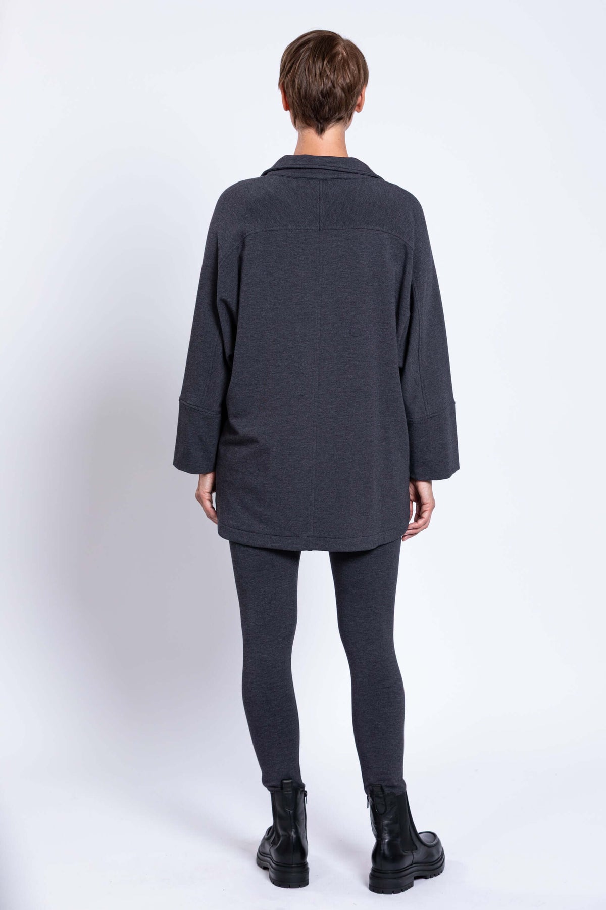 Back view of woman wearing a charcoal grey dolman sleeve jacket and matching leggings