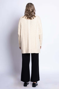 Back view of woman wearing a cream cable knit cardigan displaying the textured knit pattern