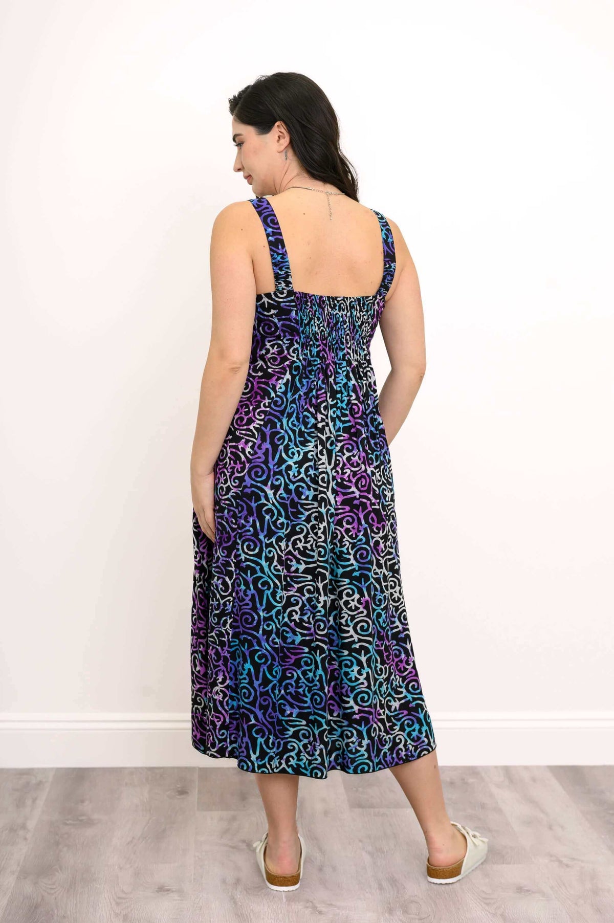 Back view of woman in a fitted, sleeveless dress with blue and purple swirl pattern