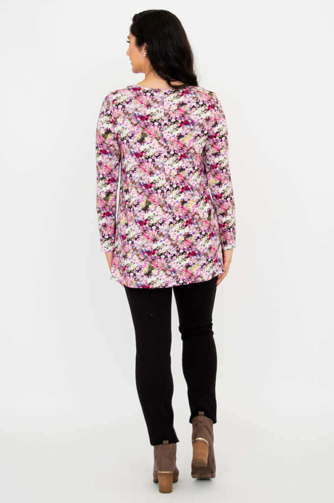 Back view of floral A-line tunic top worn with black pants and ankle boots