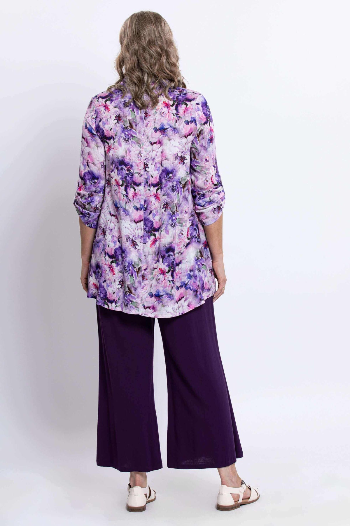 Back view of floral tunic showing length and loose fit over purple pants