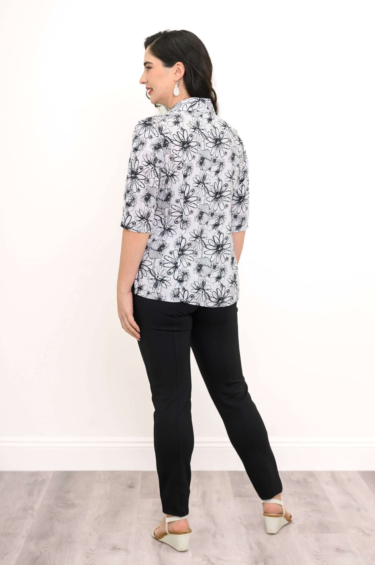 Back view of woman in floral black and white blouse with elbow sleeves