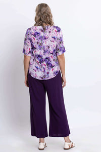 Back view of woman in floral purple blouse and wide-leg purple pants
