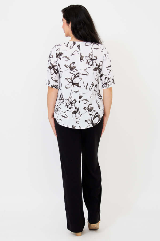 Back view of woman in white floral print blouse and black pants