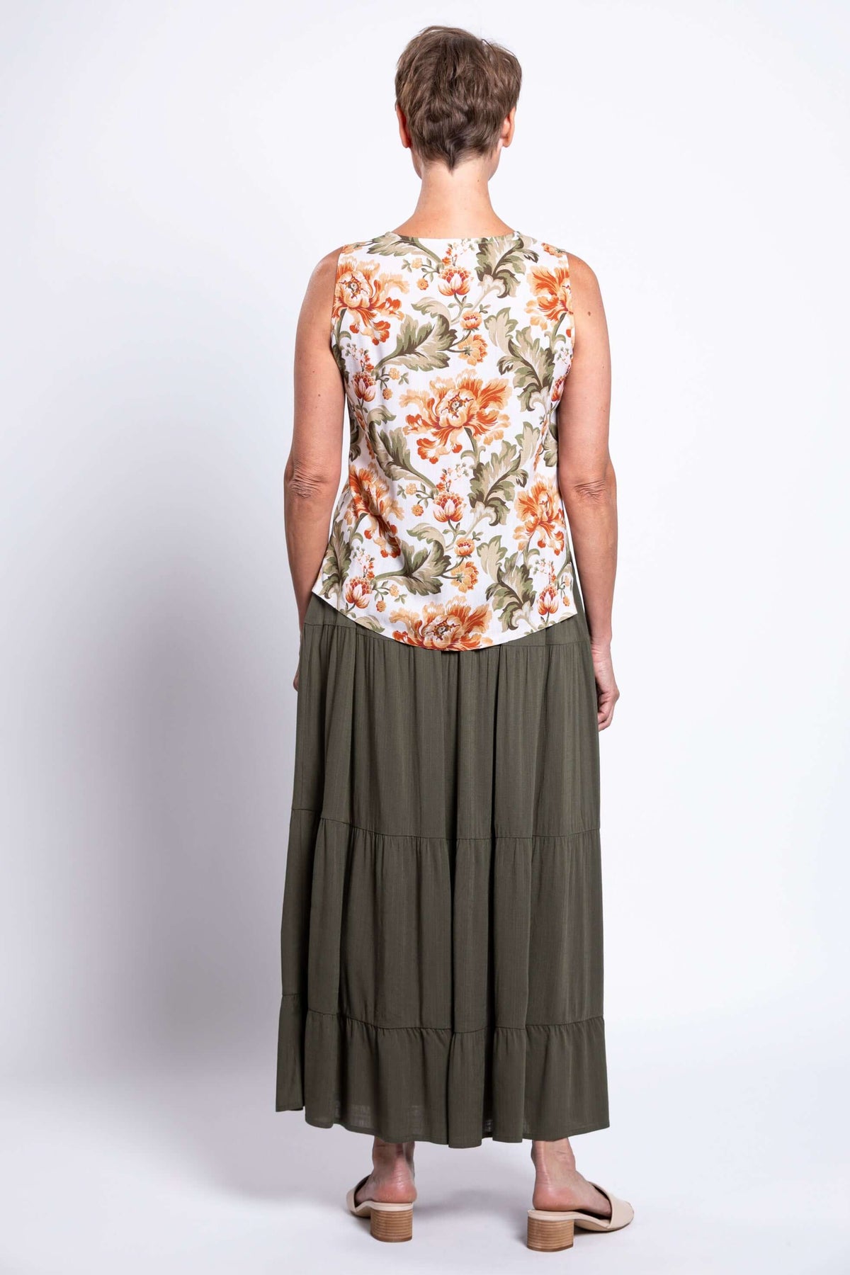 Back view of woman wearing a floral V-neck sleeveless cropped tank top and olive skirt